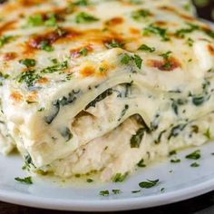 a white plate topped with lasagna covered in cheese and spinach toppings