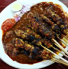 a white plate topped with meat covered in gravy and chopsticks next to onions