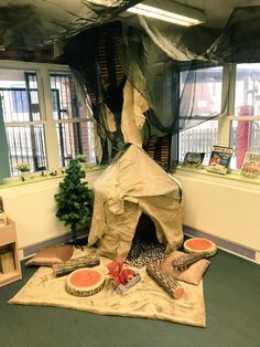 an indoor play area with various items on the floor, including a tent and trees