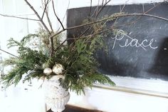 a vase filled with greenery next to a chalkboard that says peace on it