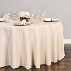 the table is set with wine glasses, plates and napkins on top of it