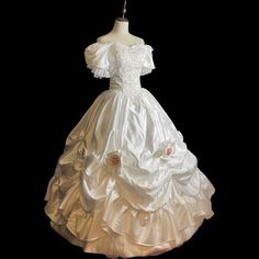 a white wedding dress on a mannequin with ruffles and flowers in the skirt