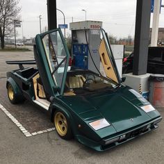 a green sports car parked at a gas station with its doors open and the hood up