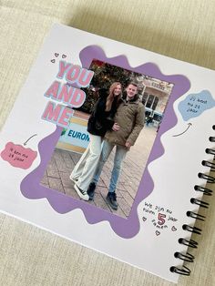 a couple standing next to each other in front of a notebook with the words you and me on it