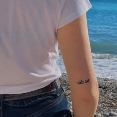 a person with a small tattoo on their arm near the water's edge,