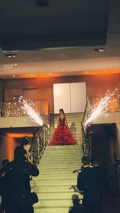 a woman in a red dress is walking down the stairs with sparklers on her head