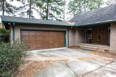 a brick house with two garages and trees in the background