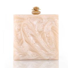 a white marble box with a gold ring on it's top and an intricately designed handle