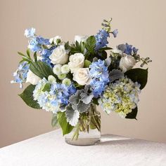 a vase filled with blue and white flowers on top of a table next to a pink background