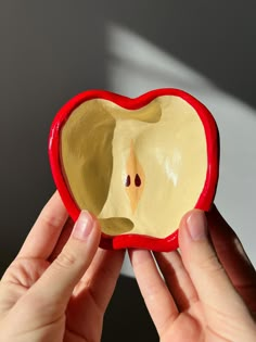 a person holding an apple shaped object in front of their face and the other hand