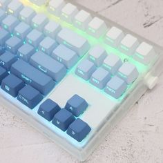 a close up of a keyboard with blue keys on a white surface and green light coming from behind it