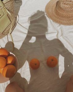 the shadow of two people on a table with oranges and a straw hat next to them