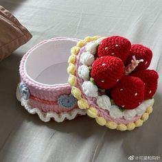 a crocheted basket with strawberries in it sitting on a bed next to a pillow