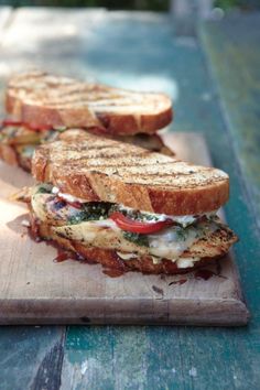 two grilled sandwiches sitting on top of a wooden cutting board