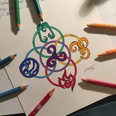 several colored pencils are laying on top of a piece of paper with an intricate design