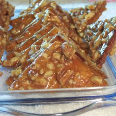 there are many pieces of food in the glass dish on the counter top, and one piece is covered with nuts