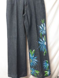 a pair of jeans with blue flowers painted on them