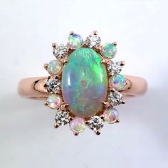 an opal and diamond cluster ring on a white surface with the center stone surrounded by smaller opals