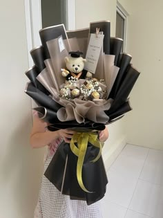 a woman holding a bouquet of chocolates with a teddy bear in the middle,