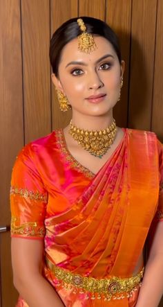 a woman in an orange and gold sari