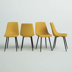 three yellow chairs sitting next to each other in front of a white wall with black legs