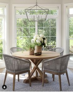 a dining room table with four chairs and a vase filled with flowers on top of it