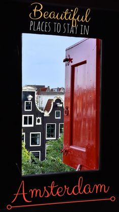 a red door is open in front of some black and white buildings with green trees