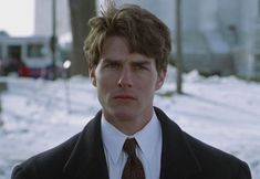 a man wearing a suit and tie standing in the snow