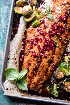 salmon with pomegranates and brussel sprouts on a baking sheet