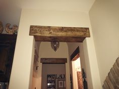 an open doorway leading to another room with pictures on the wall and wood beams above it