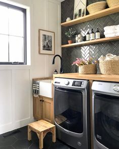 a washer and dryer in a small room with open shelving on the wall