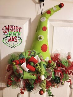 a christmas wreath hanging on the front door decorated with candy canes and elf hats