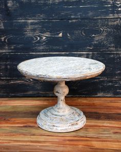 an old white cake plate sitting on top of a wooden table next to a wall