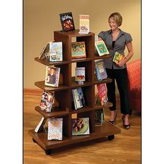 a woman standing next to a book shelf filled with lots of books on top of a hard wood floor