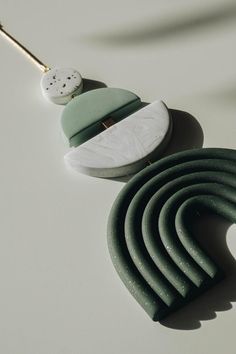 a green and white necklace is laying on a table