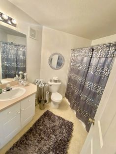 a bathroom with a toilet, sink and shower curtain in it's center area