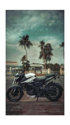 a black and white motorcycle parked in front of palm trees