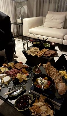 a table filled with different types of food on top of a wooden table next to a couch