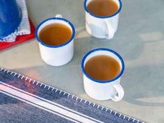 three cups of coffee sitting on top of a table next to a blue and white towel