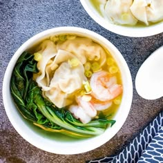 two bowls filled with dumplings and vegetables on top of a table