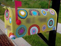 a brightly colored mailbox sitting on the side of a road next to a sidewalk