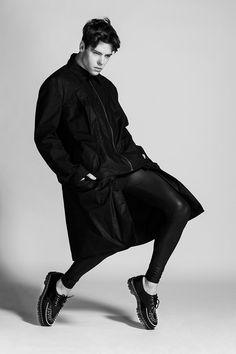 a man in black is posing with his legs spread out and shoes on the ground