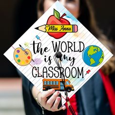 a woman holding up a sign that says the world is my classroom on her graduation cap