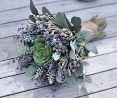 a bridal bouquet with succulents and leaves on a wooden decking area