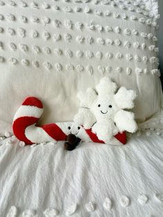 two stuffed animals laying on top of a white bed