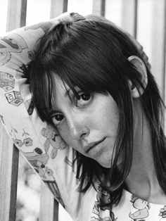 a black and white photo of a woman with her hand on her head looking at the camera