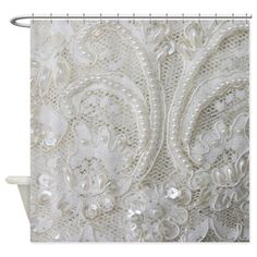 a shower curtain with white lace and pearls on it