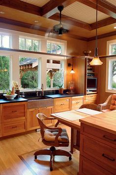 a kitchen with wooden cabinets and an island in front of two windows that look out onto the yard