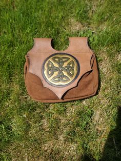 a brown leather bag sitting on top of green grass