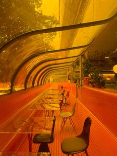 there are many chairs and tables on the floor in this long room with orange walls